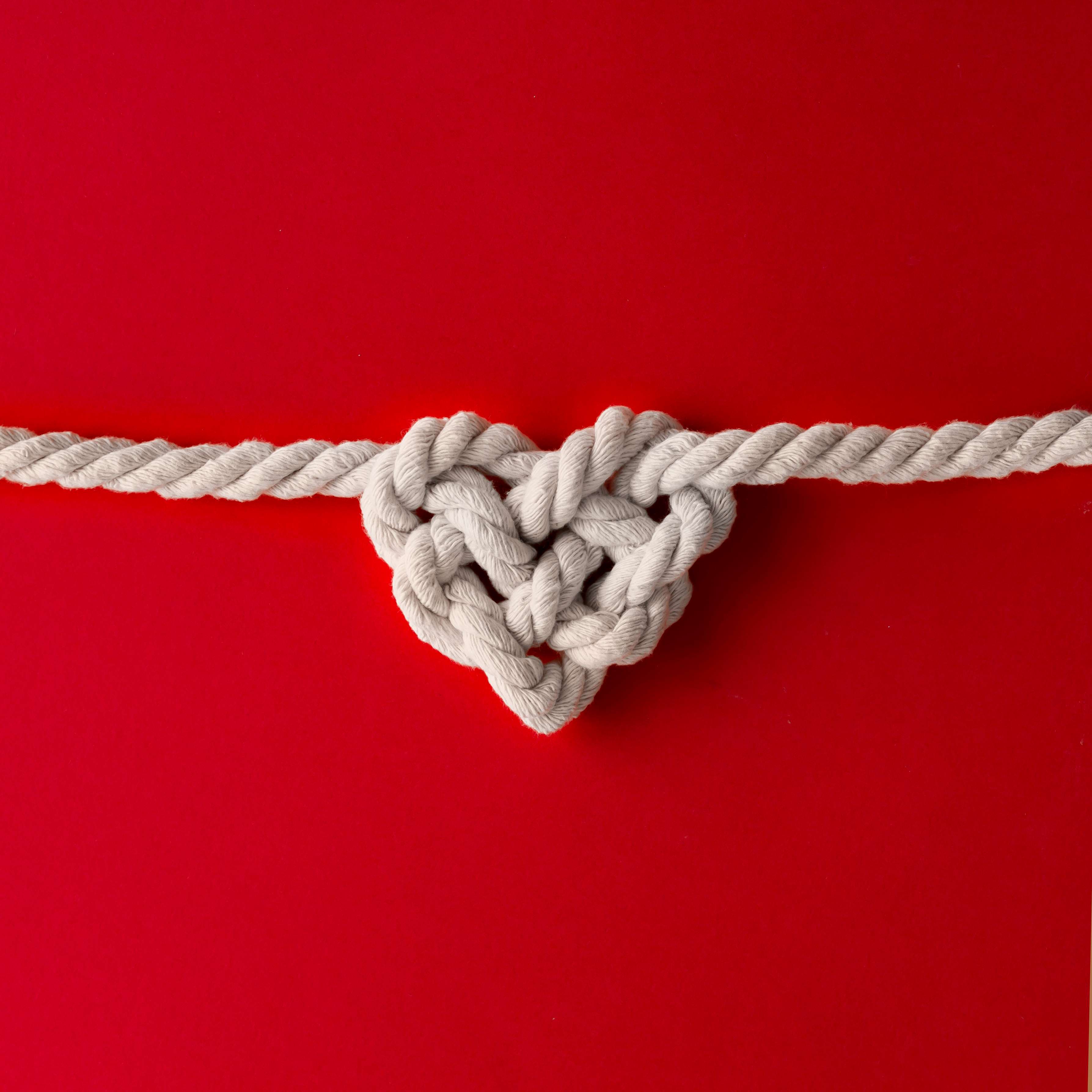 white-rope-in-heart-shape-knot-on-red-background-2021-08-27-11-12-45-utc_r
