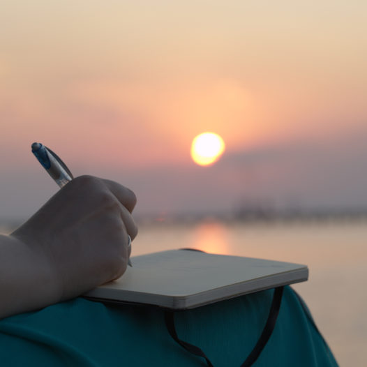 Woman writing in her diary at sunset